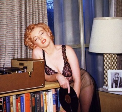 Marilyn Monroe, tired, leaning next to record player in lingerie